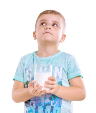 Sarı saçlı ve mavi sevimli bir küçük çocuk T-shirt lezzetli ve sağlıklı süt ya da muzlu süt ile ayakta ve örnek alıyor, beyaz bir arka plan üzerinde izole.