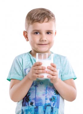 Gamze üzerinde beyaz bir arka plan üzerinde izole onun elinde bir bardak süt Holding'in yanakları ile harika bir çocuk. Güzel çocuk mavi tişört giyiyor ve taze süt bir drenaj ile ayakta.