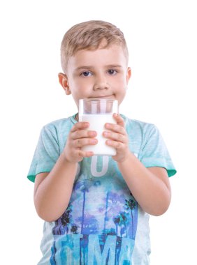 Beyaz bir arka plan üzerinde izole onun elinde bir bardak süt Holding'in gülümseyen yakışıklı çocuk. Oğlan mavi tişört giyiyor ve taze süt bir drenaj ile ayakta.