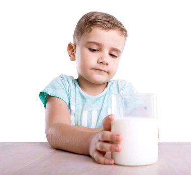 Büyük bir bardak elinde lezzetli süt dolu o bakıyor bir küçük şirin üzgün çocuk parlak mavi tişört içinde. Bir bardak süt, beyaz bir arka plan üzerinde izole tutan küçük şirin bir çocuk.