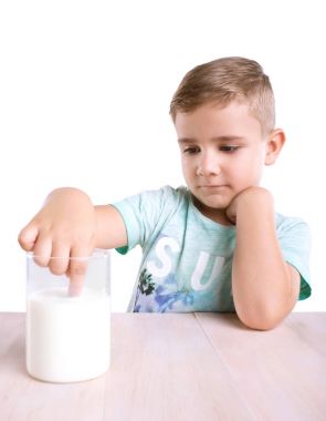 Yakışıklı ve tatlı küçük çocuk düşünceli arıyorum ve beyaz bir arka plan üzerinde izole bir süt içecek onun parmağı daldırma.