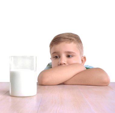Yakışıklı ve üzgün küçük bir çocuk büyük bardağın dolu organik süt, beyaz bir arka plan üzerinde izole bakıyor.