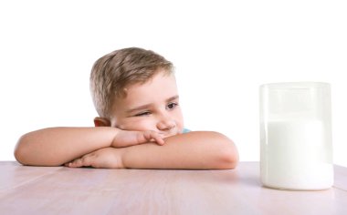 Altın saçlı biraz çok şirin çocuk kahverengi masada onun el koydu ve lezzetli süt ayakta sağ köşedeki dolu cam doğru bakar.