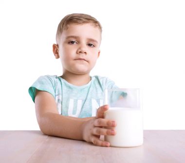 Kendine güvenen, ciddi, ama çok güzel küçük bir çocuk ile sarı saçları ve mavi T-shirt tutar sağlıklı lezzetli süt, beyaz bir arka plan üzerinde izole bir cam dolu.