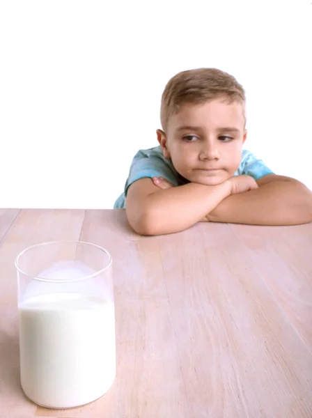 Egy aranyos kis fiú egy pohár tele tápláló tej kék pólóban. Egy aranyos kisfiú, egy pohár tej, egy fából készült asztal, elszigetelt fehér background. — Stock Fotó