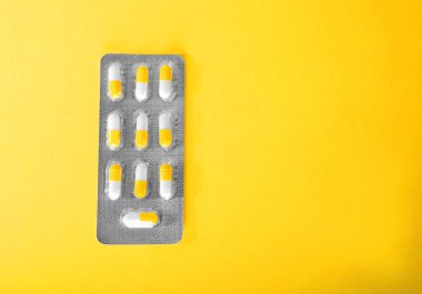 Yakın çekim simgeler parlak sarı bir arka plan üzerinde ilaç. Beyaz ve turuncu hap, uyuşturucu, blister tablet. İlaç prescripted ilaçlar.