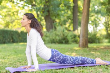 Doğal bir arka plan üzerinde konsantre bir kız. Güzel spor kız parkta bir mat. Sağlıklı yaşam tarzı. 