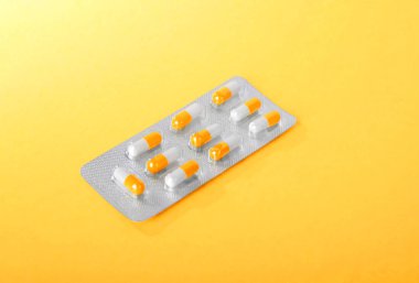 Parlak sarı bir arka plan turuncu ve beyaz ağrı kesici ışık kabarcıklar yakın çekim resmin. Prescripted uyuşturucu pachage. Tıbbi vitaminler.