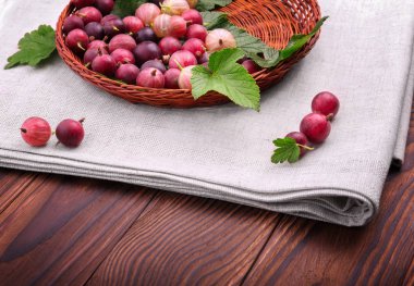 Sağlıklı ve hafif ahşap sepet içinde çok renkli bektaşi olgun. Besleyici vejeteryan kahvaltısı. Koyu kahverengi arka plan üzerinde kahverengi ahşap sandık. Renkli kırmızı meyveler yaprakları ile.