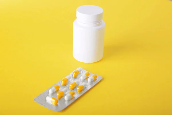 Un pequeño paquete de plata de medicamentos recetados, tabletas sobre un fondo espacioso de color amarillo brillante. Suplemento farmacéutico . — Foto de Stock