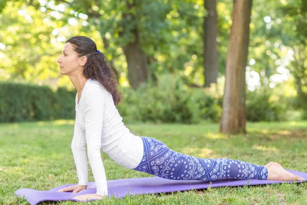 Doğal bir arka plan üzerinde konsantre bir kız. Güzel spor kız parkta bir mat. Sağlıklı yaşam tarzı. 