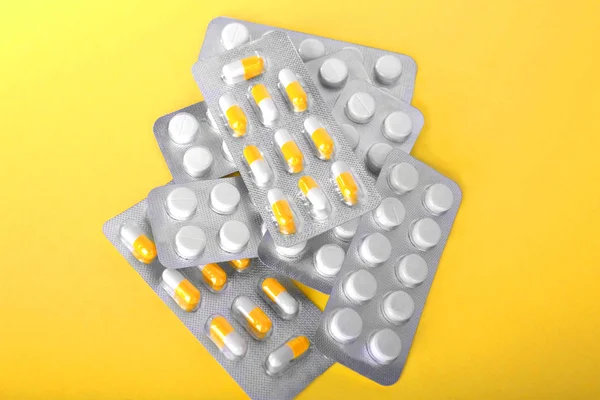 Pastillas de primer plano en paquetes sobre un fondo amarillo brillante. Diferentes antibióticos, analgésicos y medicamentos recetados en un fondo amarillo. Comprimidos del medicamento para el tratamiento . — Foto de Stock