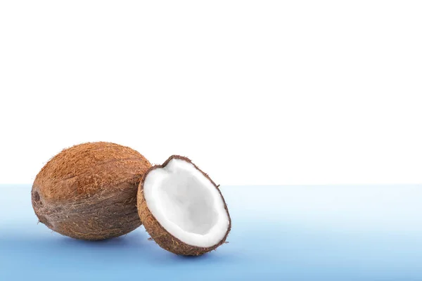 在明亮的浅蓝色背景上的棕色椰子。新鲜的椰子切成两半。美味的热带坚果充分的营养. — 图库照片
