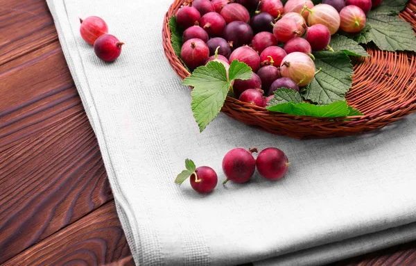 Taze zevkli farklı tonları parlak kırmızı renk bektaşi ahşap sepet içinde. Beyaz kumaş üzerine ahşap bir masa üzerinde bir ışık kahverengi sepet. Besleyici meyve madde. Renkli kırmızı meyveler.