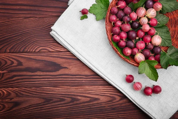 Koyu kahverengi ahşap masa üzerinde hafif kahverengi sepet içinde yeşil yaprakları ile çok renkli bektaşi sulu, sağlıklı, olgun. Bektaşi tonlarını parlak kırmızı renk.