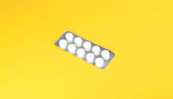 Zářivě bílý antibiotika na slunném žlutém pozadí. Tablety, detail. Léčba. — Stock fotografie