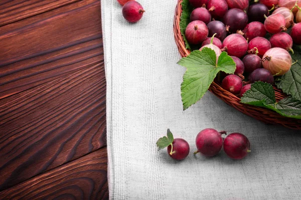 Hafif kahverengi sepet içinde yapraklarla lezzetli kırmızı bektaşi. Sağlıklı organik çilek koyu kahverengi masada. Sulu, ham, taze, lezzetli, sağlıklı, besleyici kavramı.