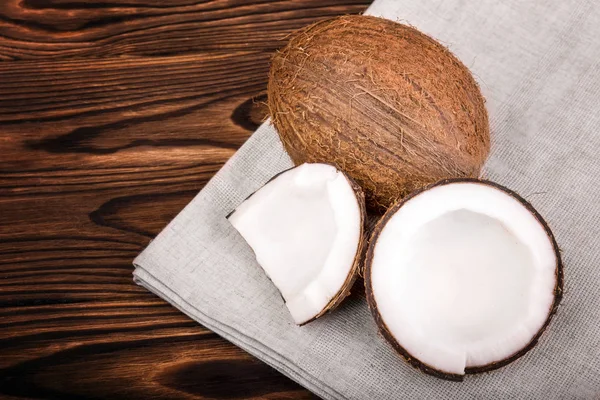 Close-up hermosos cocos sobre un fondo marrón. Fresco cortado en rodajas de coco sobre una tela gris. Componentes vegetarianos . — Foto de Stock