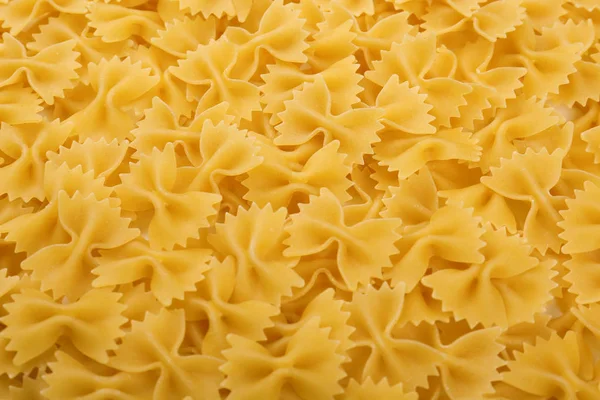 Nyers olasz farfalle tészta. Nyers, finom és világos sárga textúra közelről. Macarons, tészta, tészta, spagetti közelről. — Stock Fotó