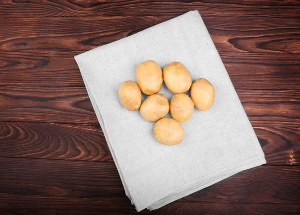 Питательный, свежий, органический новый картофель в серой ткани на темно-коричневом деревянном столе. Неприготовленные и вкусные свежие овощи. Летний урожай картофеля . — стоковое фото