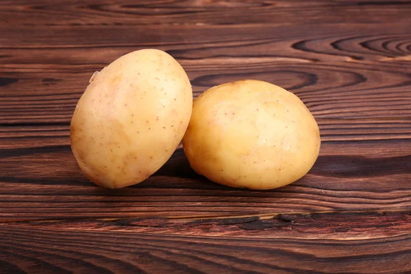Obraz dwa surowe, a nowe ziemniaków na ciemno brązowy drewniany stół. Dobrej jakości ziemniaków. Smaczny młodych ziemniaków brązowy światła. Świeże warzywa. — Zdjęcie stockowe