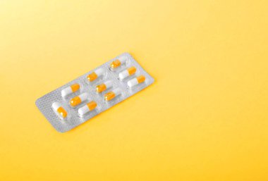 Parlak sarı bir arka plan üzerinde renkli aliminin. Bir tek parlak paketi çok renkli uyuşturucu dolu. Vitaminler ile küçük hap.