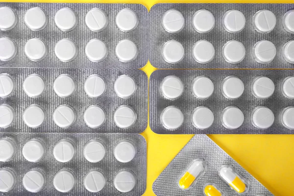Uma vista superior de pacotes com pastilhas redondas, sobre um fundo brilhante. Aspirina e analgésicos terapêuticos de cura. Saudáveis vitaminas. — Fotografia de Stock