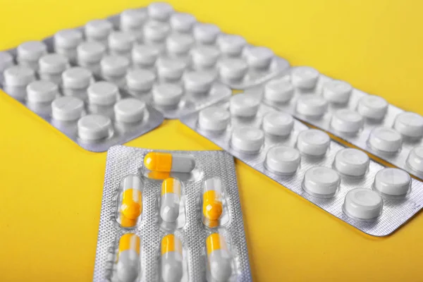 Un primer plano envases brillantes con drogas sobre un fondo amarillo. Estupefacientes y antibióticos recetados en tabletas. Ciencias médicas . — Foto de Stock