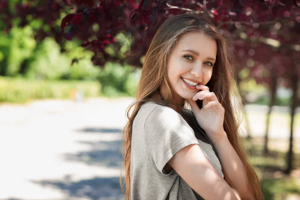 Uma bela loira sobre um fundo claro e ensolarado. Uma garota adorável relaxante e rindo ao ar livre. Uma jovem posando em um parque. — Fotografia de Stock
