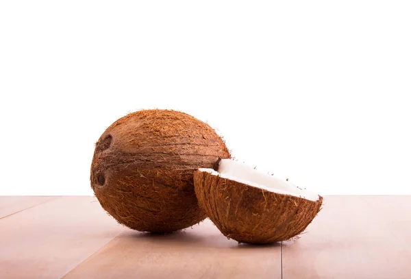Noix de coco hawaïennes brunes sur une table en bois clair, isolées sur un fond blanc. Fruits de coco crus. Noix de coco entières et coupées . — Photo