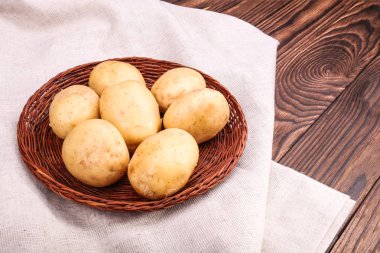 Çiğ patates hasat. Organik ve besleyici patates bir kumaş ve koyu kahverengi ahşap bir masa. Taze sebze. Sağlıklı bir diyet için sebze.