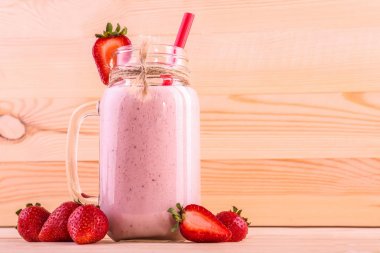 Pembe güler yüzlü lezzetli kırmızı saman ve çilek çevresinde ve bir üst açık kahverengi renkli bir cam ile. Sağlıklı meyve. Pembe yüzlü.