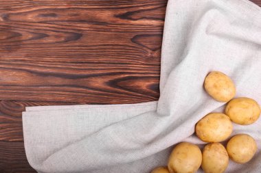 Ahşap arka plan üzerinde taze, organik, ham ve yeni patates. Gri kumaş üzerinde sağlıklı yeni patates close-up. Yaz hasat.