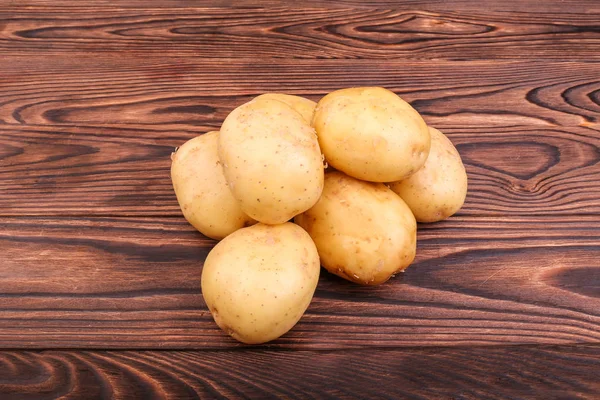 Patatas crudas, frescas y sin cocer sobre un fondo de madera marrón oscuro. Verduras frescas. Alimento natural de agricultura fresca vegetal. Patatas nuevas crudas, limpias y de color marrón claro . —  Fotos de Stock