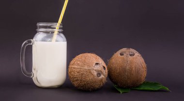 Olgun ve organik Hindistan cevizleri, bir kompozisyon koyu mor arka plan üzerinde doğal süt ile büyük mason kavanoza. Lezzetli tropikal ve egzotik vitaminler.