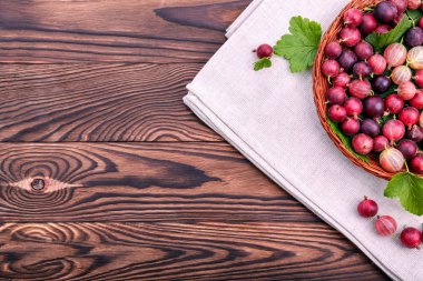 Koyu ahşap bir masa üzerinde kahverengi bir sepet içinde yeşil yaprakları ile çok renkli bektaşi sağlıklı, sulu ve olgun. Bektaşi tonlarını parlak kırmızı renk.