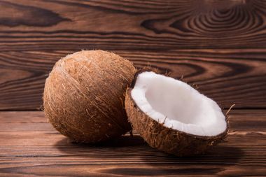 Yakın çekim bir çift koyu kahverengi ahşap arka plan üzerinde tropikal Hindistan cevizleri. Egzotik bir bütün kahverengi coco ve kırık içinde yarım Hindistan cevizi. Tropikal Kuruyemiş.