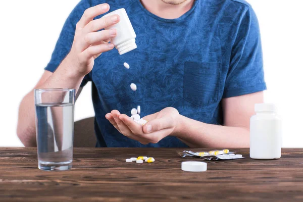 Um homem derramando comprimidos isolados em um fundo branco. Prevenção de suicídio. Tratamento médico. Doença, conceito de depressão . — Fotografia de Stock