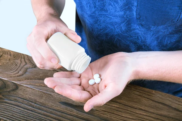 Un hombre tomando pastillas con un fondo brillante. Medicamentos recetados, aspirina, analgésicos. Tratamiento farmacéutico. Prevención del suicidio . — Foto de Stock
