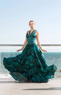 Deniz arka plan üzerinde uzun siyah yeşil elbiseli çekici kız. Uzun bir yeşil akan güzel kadın elbise denize yakın. Bir yaz tatili mükemmel bir kadın.