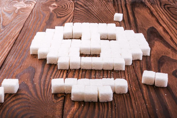 头骨符号由糖多维数据集。块糖在一个木制的背景上。糖成瘾概念。不健康成分. — 图库照片