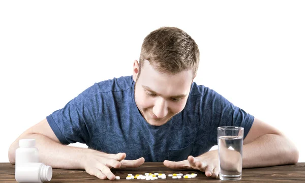 Ein lächelnder Junge mit Medikamenten auf weißem Hintergrund. ein Patient, der Tabletten mit einem Glas Wasser einnimmt. Erfolgreiche Behandlung. — Stockfoto