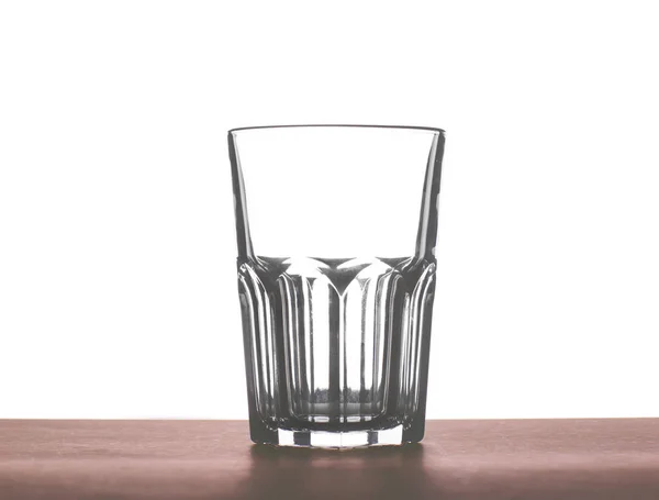 Un gran vaso vacío hermoso para el agua, jugo o leche sobre una mesa de madera marrón oscuro, aislado sobre un fondo blanco . — Foto de Stock