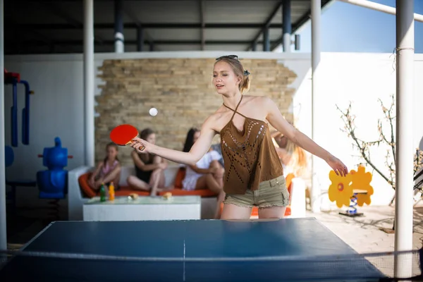 Una bella e giovane ragazza gioca a ping pong presso il centro di intrattenimento. Una ragazza attraente in abiti casual gioca a ping pong. Sport . — Foto Stock
