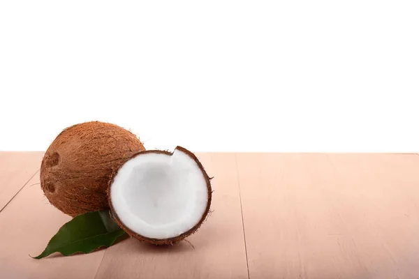 Uma imagem de close-up de cocos isolados em um fundo branco. Um cracking e um coco inteiro em uma mesa de madeira. Frutos de verão . — Fotografia de Stock