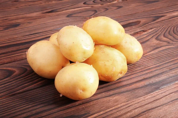 Patatas crudas, frescas y sin cocer sobre un fondo de madera marrón oscuro. Verduras frescas. Alimento natural de agricultura fresca vegetal. Patatas nuevas crudas, limpias y de color marrón claro . — Foto de Stock