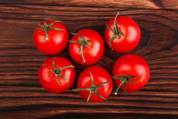 Unos tomates brillantes sobre un fondo de madera oscura. Sabrosas verduras maduras de verano, primer plano. Cosecha de verano de verduras ecológicas, vista superior . —  Fotos de Stock