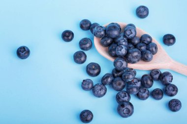 Mavi bir arka plan üzerinde üstten görünüm taze yaban mersini. Sulu ve sağlıklı yaban mersini bir tahta kaşık içinde. Hasat yaban mersini.