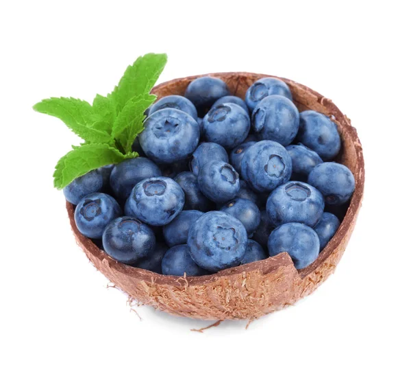 Arándanos y hojas verdes en una cáscara de coco. Bonitos arándanos aislados sobre un fondo blanco. Refrescar las frutas de verano . — Foto de Stock