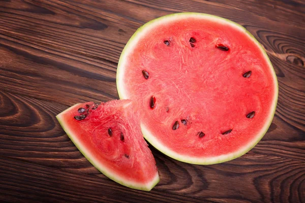 Pohled shora šťavnatý meloun snížit na polovinu. Červený meloun kusů na dřevěné pozadí. Čerstvé a sladké zdravé občerstvení. — Stock fotografie